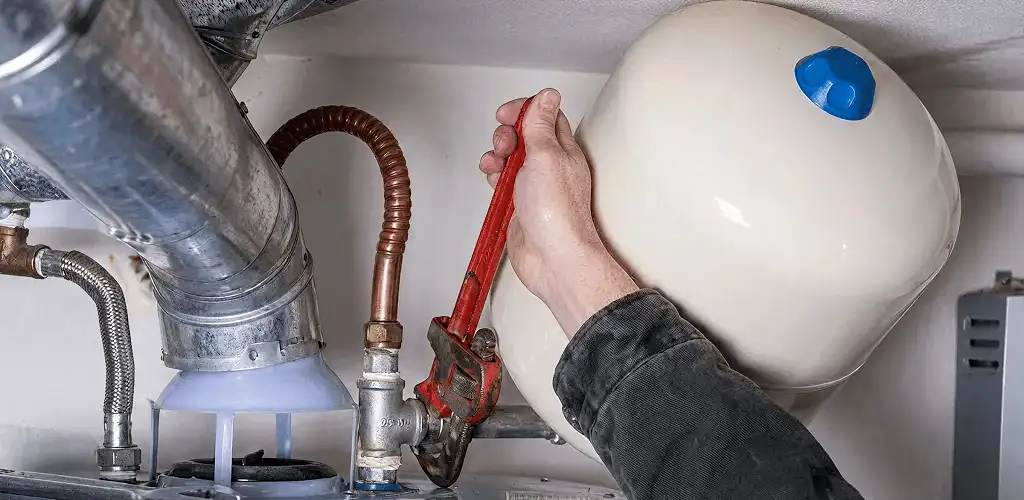 Water heater repair technician tightening plumbing connections near a tank unit in Pasadena, CA